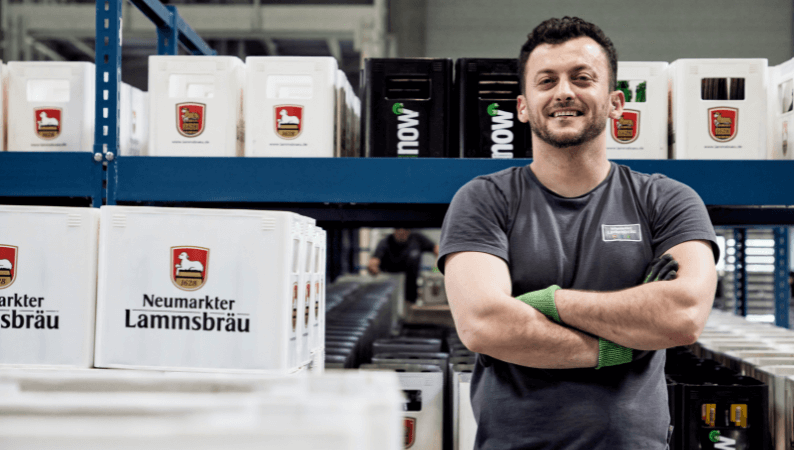 Mann selbstbewusst und lachend zwischen Lammsbräu Kisten